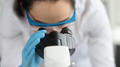 Woman doctor scientist looking through microscope in clinic.Macro study in laboratory concept